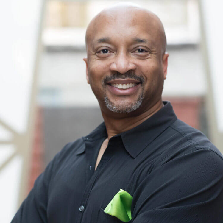 A smiling man with a goatee, wearing a black shirt and a green pocket square in Central Oregon.