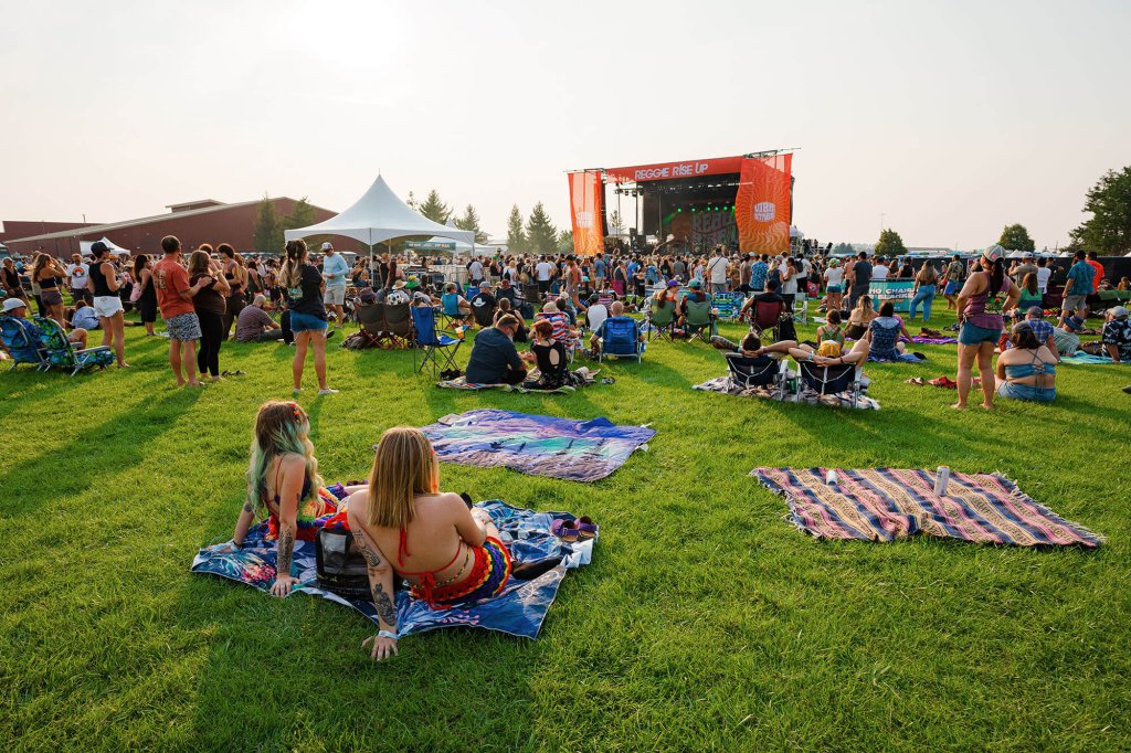 A vibrant outdoor concert scene with a large crowd enjoying music on a grassy field in Central Oregon.