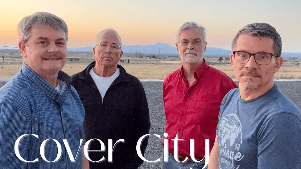 Four men pose together at sunset, with mountains in the distance in Central Oregon.