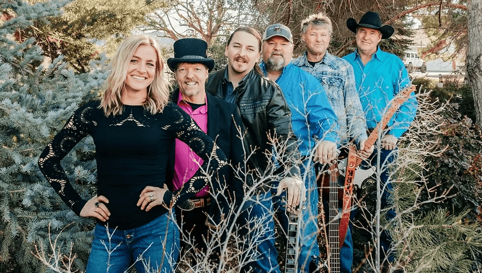 A group of five men and one woman pose together outdoors, smiling in Central Oregon.