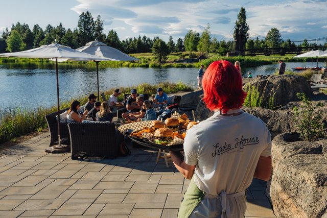 A person with red hair serves burgers at a lakeside gathering in Central Oregon.