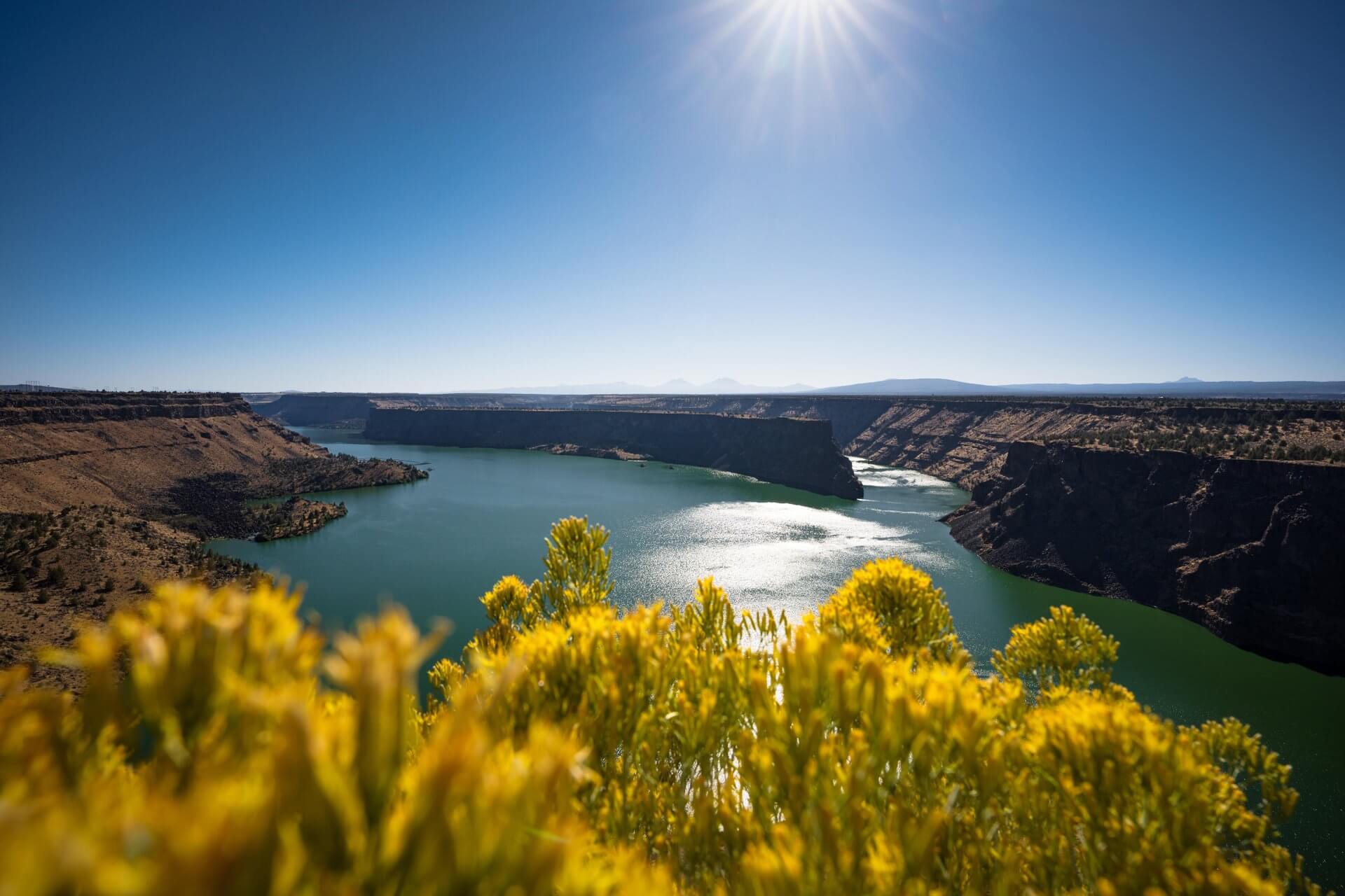 A stunning desert landscape with a vibrant green river winding through deep canyons in Central Oregon.