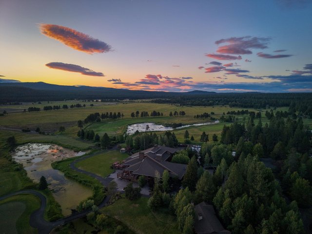 Sunset over a serene landscape with a house nestled among trees in Central Oregon.