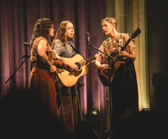 Four musicians perform on stage, playing guitars and singing in Central Oregon.