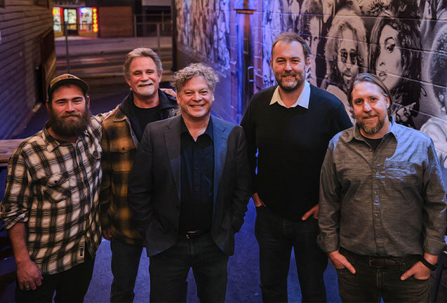 Five men standing together in a narrow alleyway, smiling at the camera in Central Oregon.