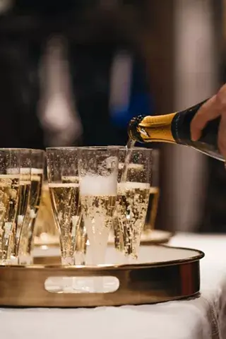 A hand pours champagne into a tray of glasses, creating a festive atmosphere in Central Oregon.