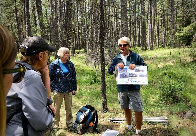A group of hikers in a forest, one person showing a map to the others in Central Oregon.