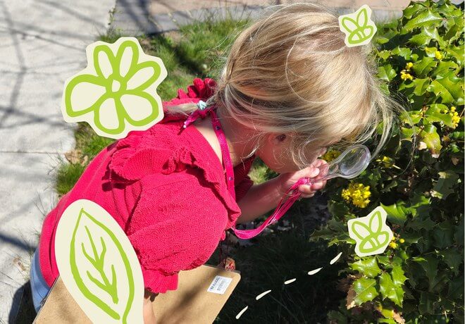 A young girl in a red dress uses a magnifying glass to examine yellow flowers in a garden in Central Oregon.