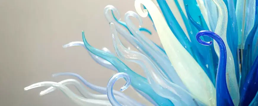 A vibrant glass sculpture with swirling blue and white tendrils resembling underwater sea anemones in Central Oregon.
