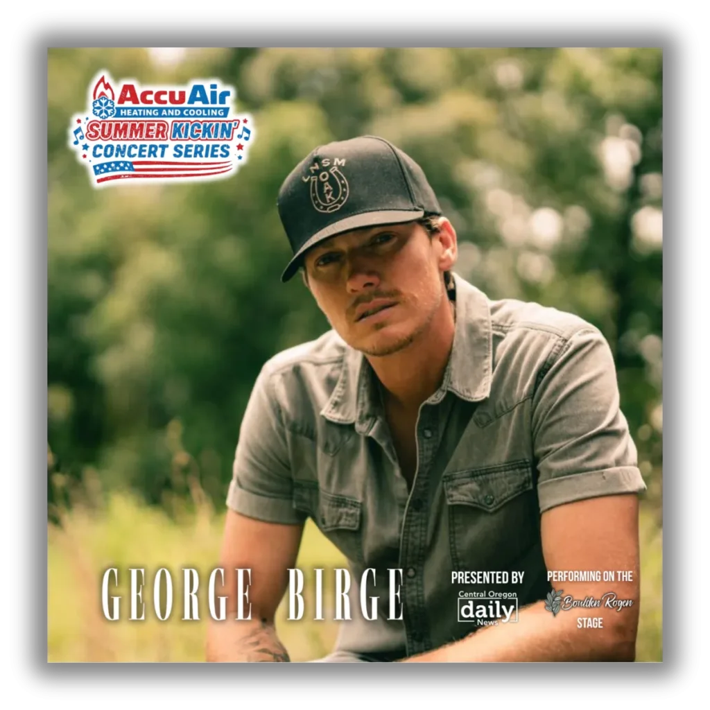 George Birge, a country music artist, is seated outdoors wearing a black cap and a denim shirt, with a backdrop of lush greenery in Central Oregon.