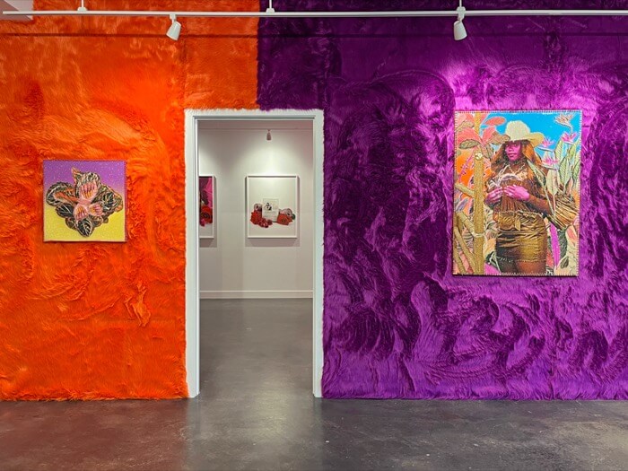 A vibrant art gallery with walls covered in orange and purple fur-like fabric, showcasing colorful paintings and sculptures in Central Oregon.