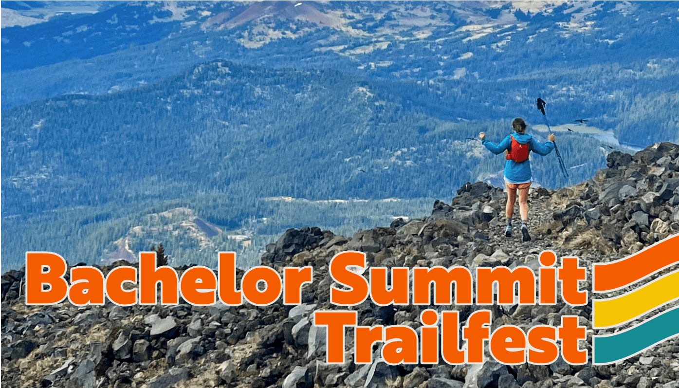A hiker stands triumphantly on a rocky summit, overlooking a breathtaking mountain landscape at Bachelor Summit Trailfest in Central Oregon.