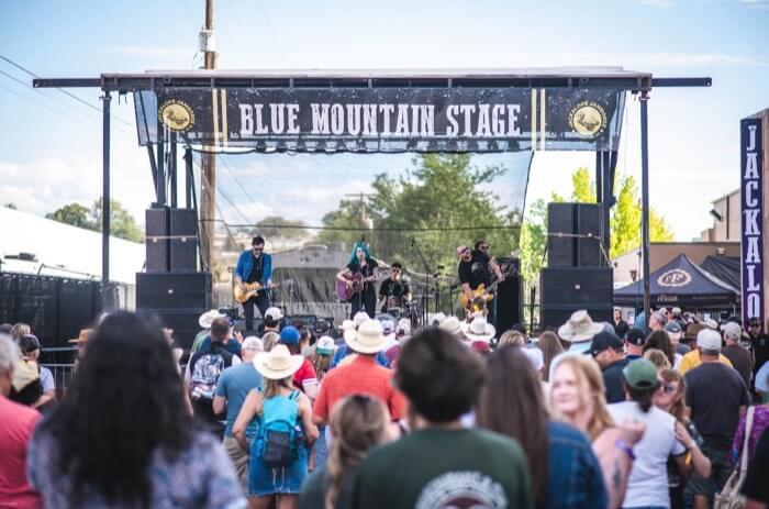 A lively crowd at the Blue Mountain Stage, enjoying a band performance under a clear sky in Central Oregon.