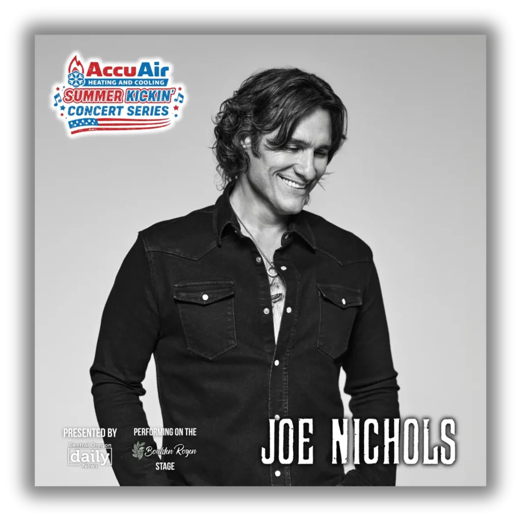 Joe Nichols, a country music artist, is smiling warmly in a black and white photograph, wearing a dark denim shirt with the top buttons undone, showcasing a necklace. He is part of the AccuAir Summer Kickin' Concert Series in Central Oregon.