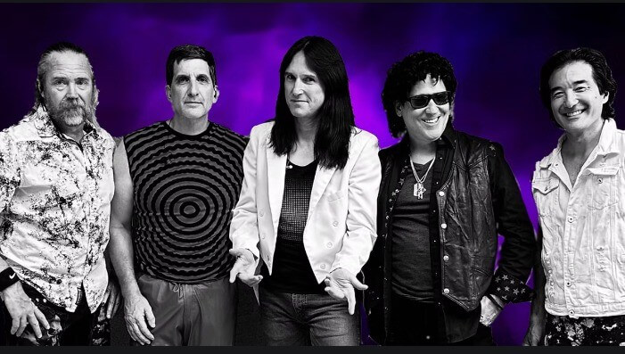 Five musicians pose together in a studio setting, dressed in stylish rock attire in Central Oregon.