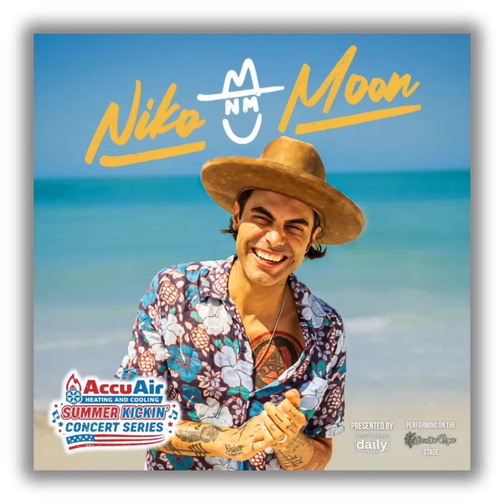 A man in a floral shirt and cowboy hat smiles on a beach with the ocean in the background in Central Oregon.