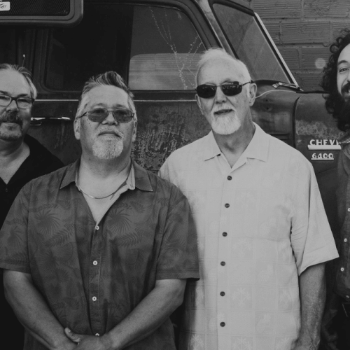 Four men standing together in front of a vintage truck, smiling at the camera in Central Oregon.