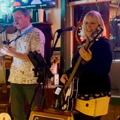 A man and woman perform music together, with the man playing a ukulele and the woman playing a guitar in Central Oregon.