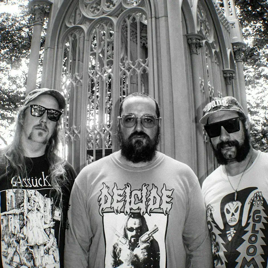 Three men in metal band t-shirts pose in front of an ornate gothic archway in Central Oregon.