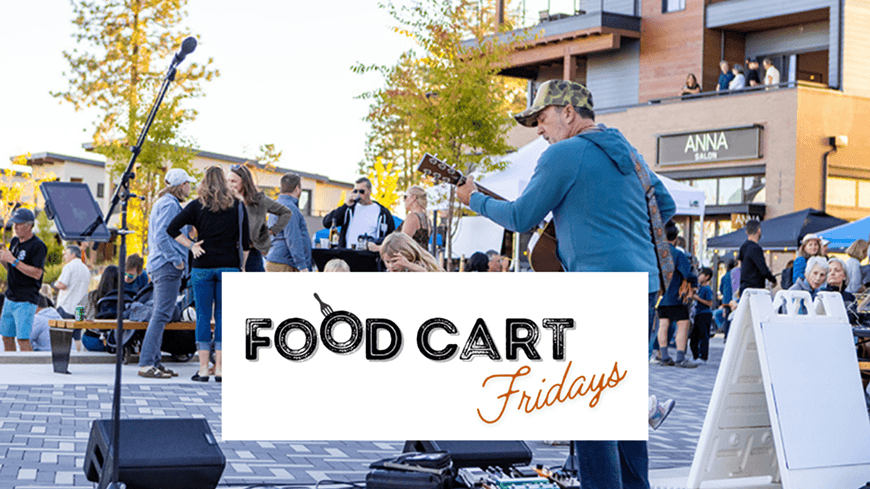 A lively outdoor event with a musician playing guitar, surrounded by food carts and a crowd enjoying the evening in Central Oregon.