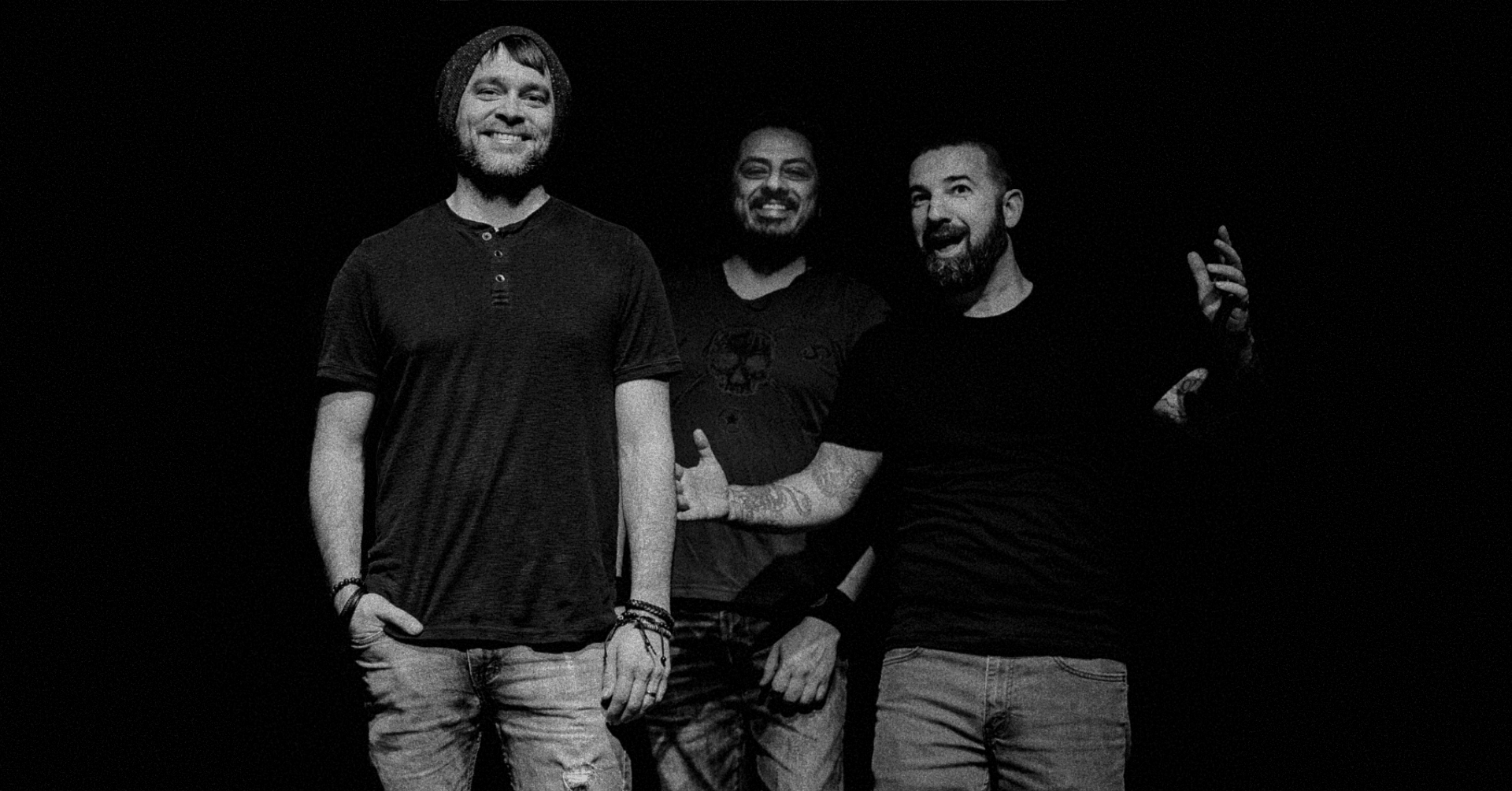 Three men standing together, smiling and gesturing, in a dark setting in Central Oregon.