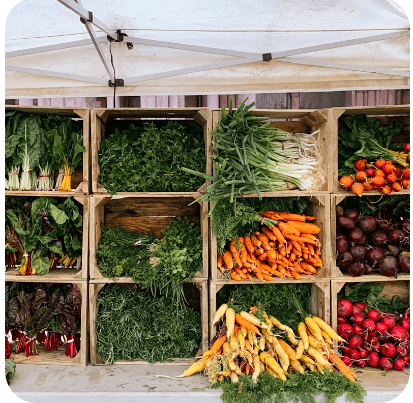 Assorted fresh vegetables displayed in wooden crates at a farmers market in Central Oregon.