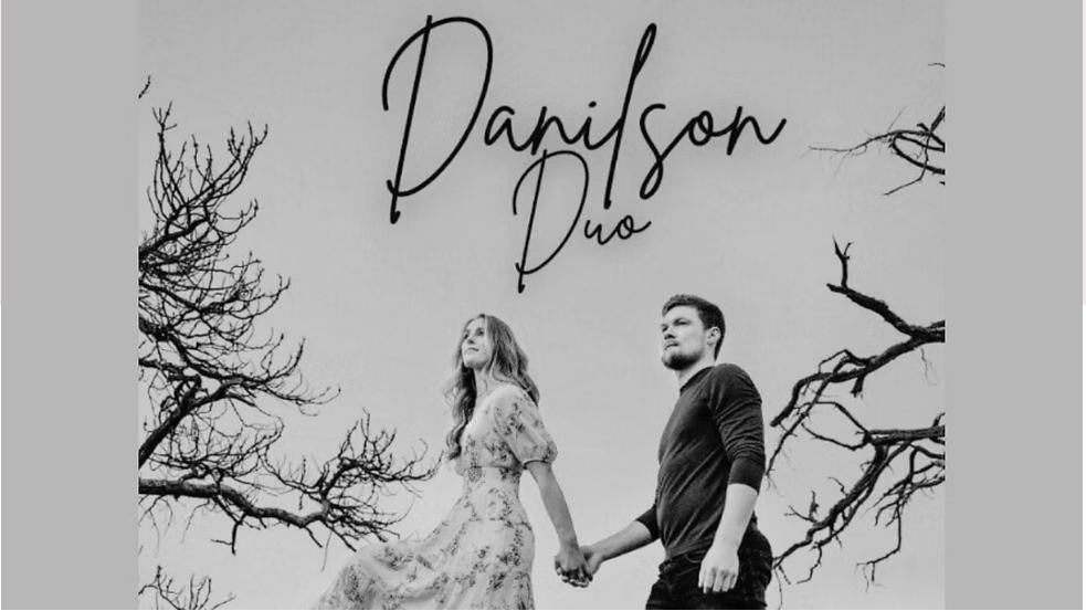 A couple holding hands, standing amidst barren trees under a clear sky in Central Oregon.