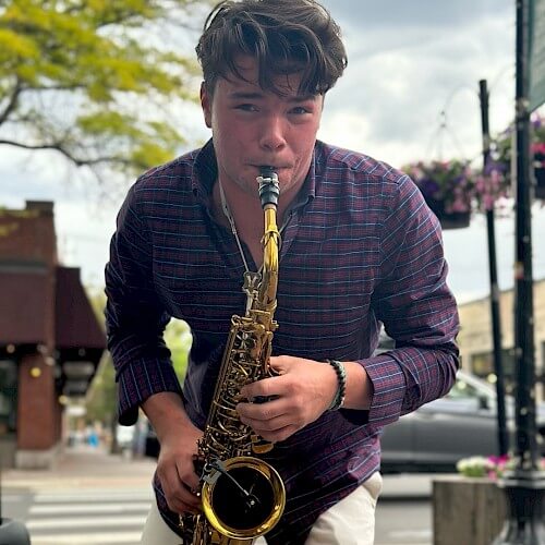 A young man passionately playing the saxophone on a city street corner in Central Oregon.