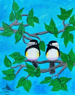 Two adorable birds with black caps and white cheeks perch on a branch surrounded by vibrant green leaves against a bright blue sky in Central Oregon.
