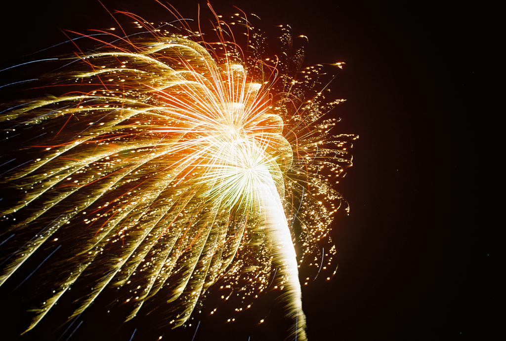 A vibrant fireworks display illuminates the night sky with a burst of golden and orange sparks in Central Oregon.