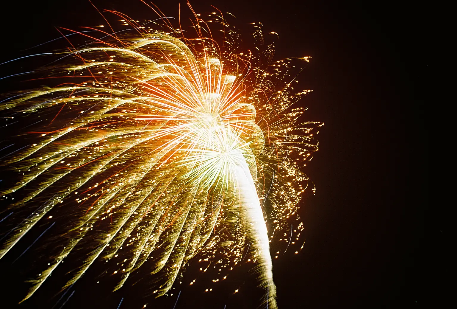 A vibrant fireworks display illuminates the night sky with a burst of golden and orange sparks in Central Oregon.