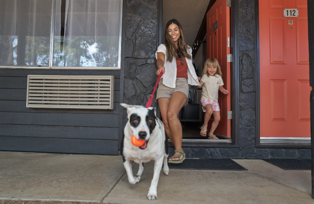 A woman and a young girl walk a dog holding a ball outside a motel in Central Oregon.
