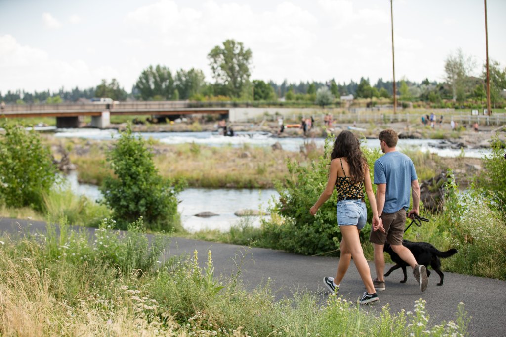 Couple walking their dog along the Deschutes River at Riverbend Park in Bend, Oregon