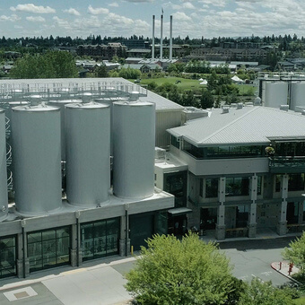 An aerial view of a brewery with large silver fermentation tanks and modern buildings in Central Oregon.