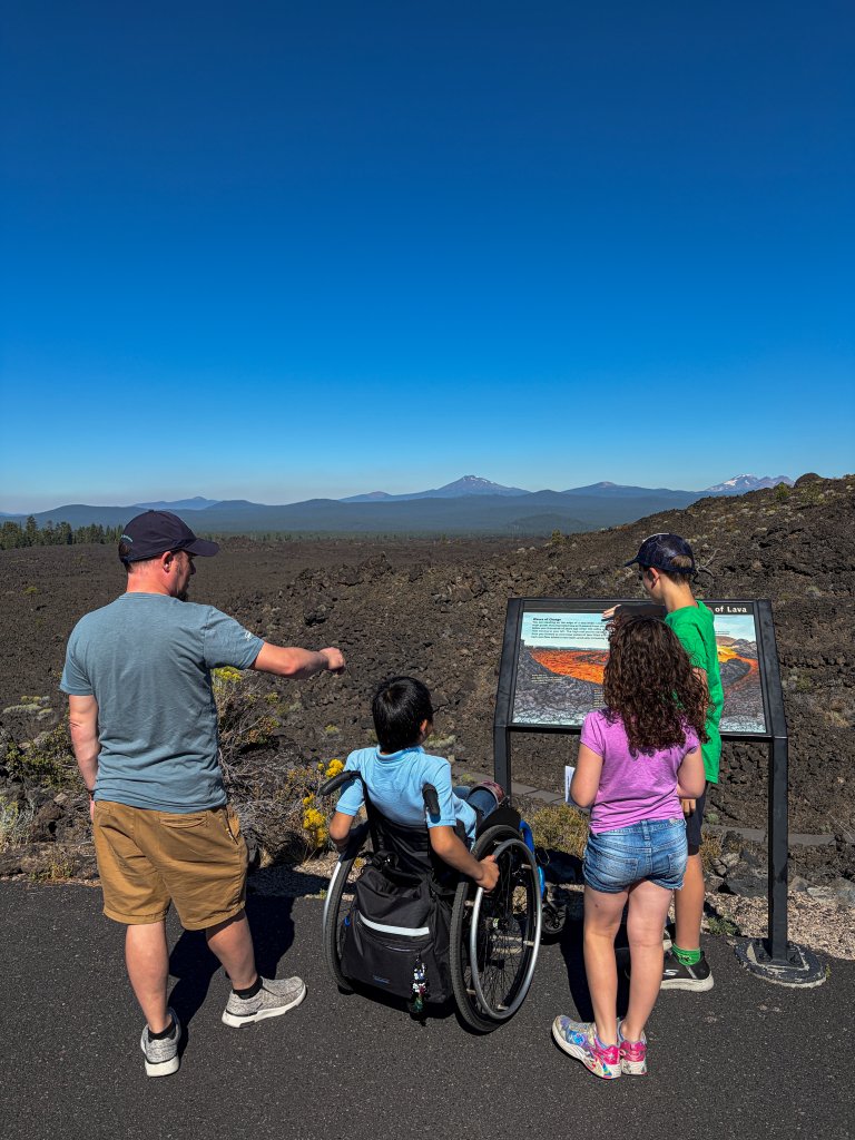 A family looks at an educational sign overlooking a vast volcanic lava field in Central Oregon.