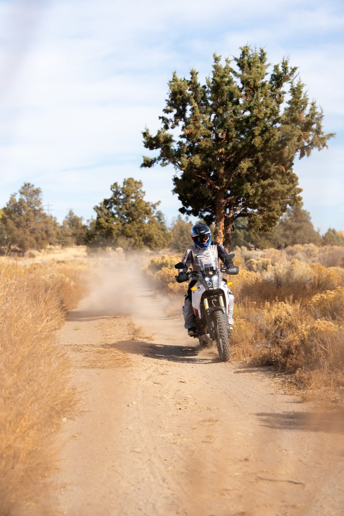A motorcyclist rides a dual-sport bike along a dusty dirt path in Central Oregon.