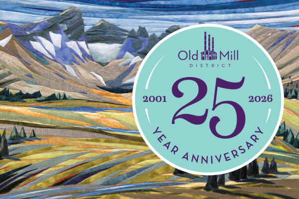 A fabric art landscape of mountains and fields with an Old Mill District anniversary logo in Central Oregon.