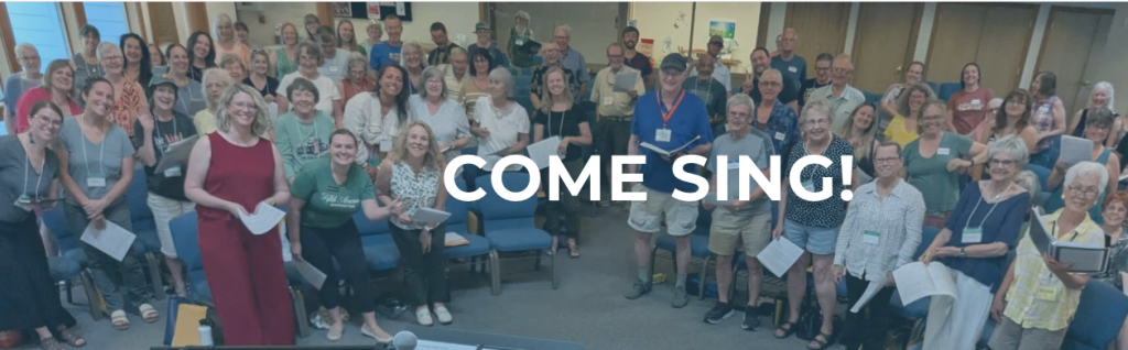 A large diverse group of people standing together in a room holding songbooks in Central Oregon.