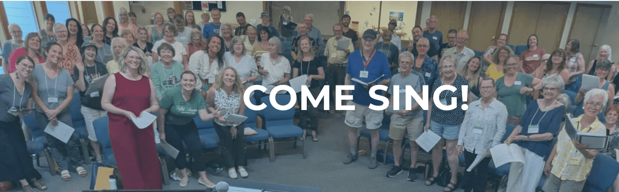A large diverse group of people standing together in a room holding songbooks in Central Oregon.