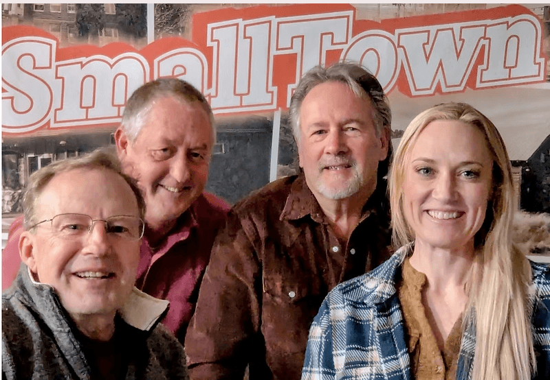 Four people smiling together in front of a Small Town sign in Central Oregon.