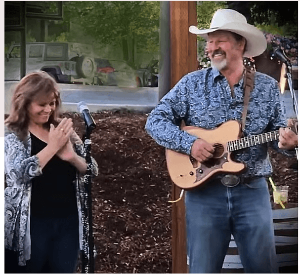 A man in a cowboy hat plays guitar while a woman claps beside him in Central Oregon.
