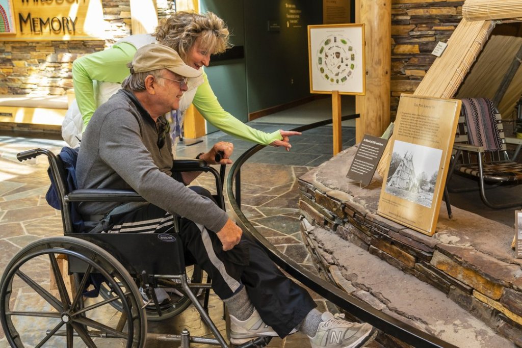 A woman points at a museum exhibit for a man sitting in a wheelchair in Central Oregon.