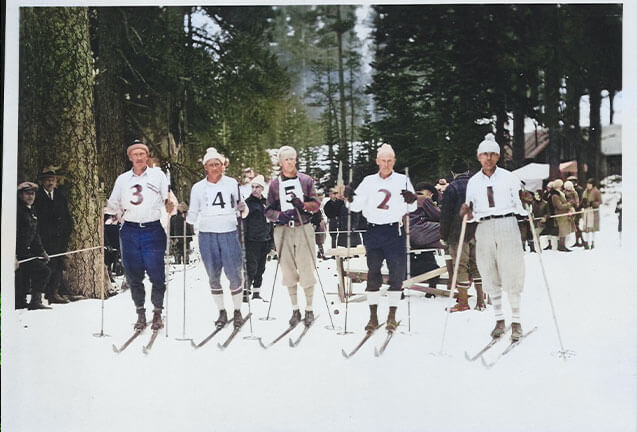 Five men in vintage ski gear with numbered bibs stand on snow in a forest in Central Oregon.
