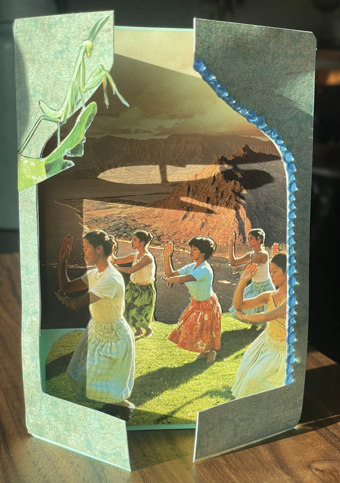 A layered paper craft featuring hula dancers in front of a mountain landscape in Central Oregon.
