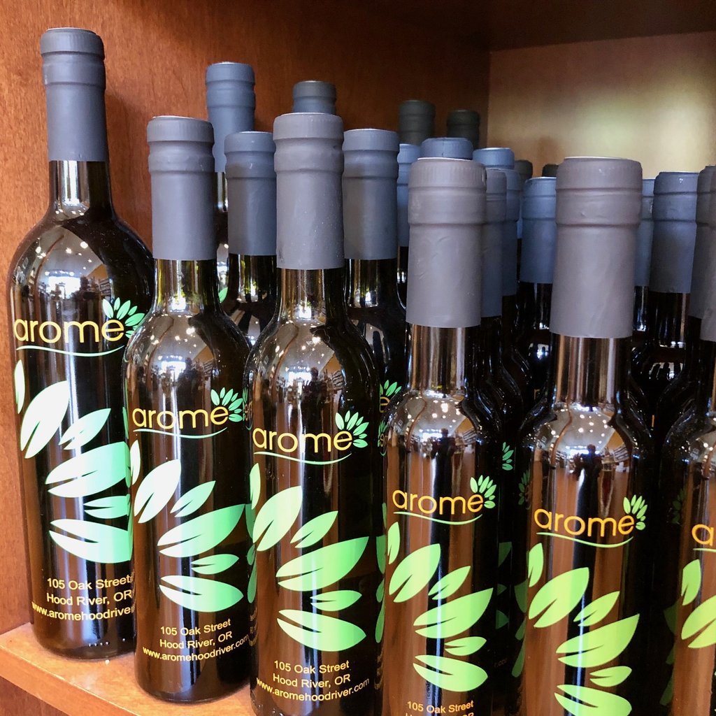 Several bottles of Arome brand oil or vinegar lined up on a wooden shelf in Central Oregon.