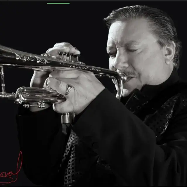 A man in a suit playing a trumpet against a black background in Central Oregon.