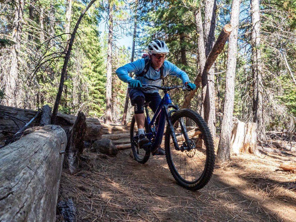 A mountain biker riding a blue bike through a sunny pine forest in Central Oregon.