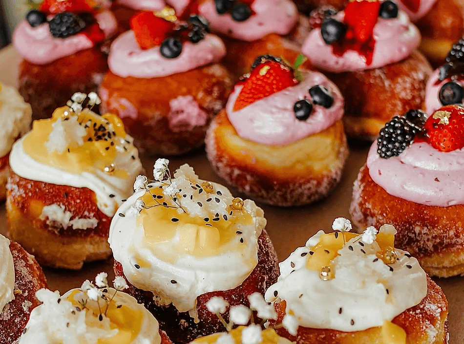 A collection of gourmet donuts topped with cream, fresh berries, and edible flowers in Central Oregon.
