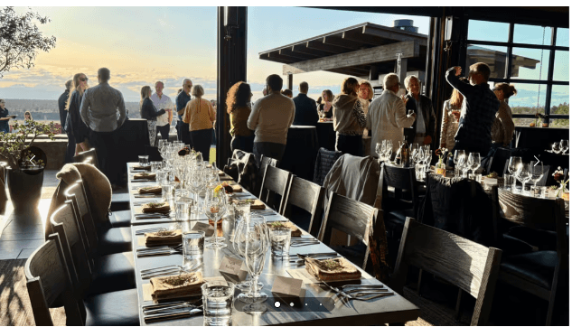 People socializing at an indoor-outdoor event with a sunset view in Central Oregon.