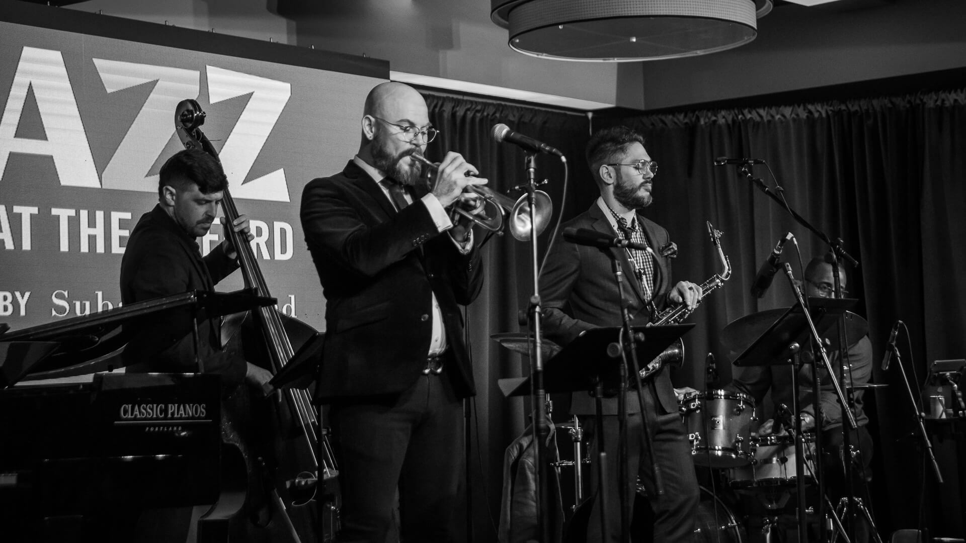 A jazz quartet performing on stage with a trumpet, saxophone, bass, and drums in Central Oregon.